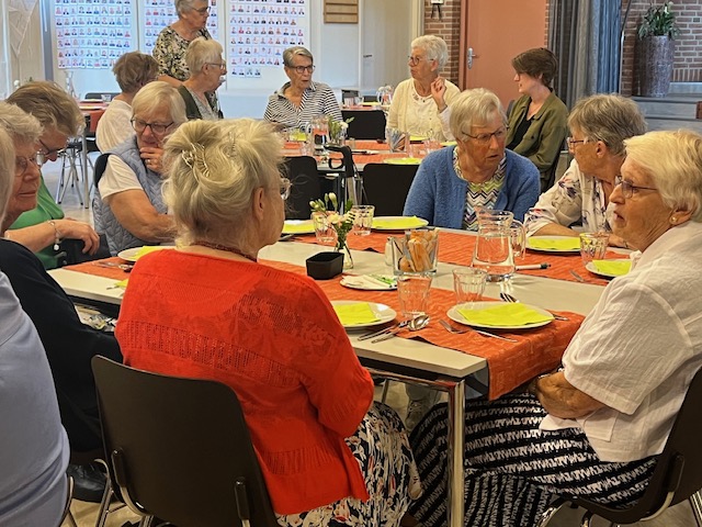 senioren aan tafels zijn met elkaar in gesprek wachtend op eten